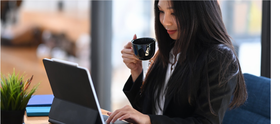 Woman reading on a device while drinking from a mug